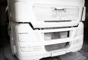Truck being washed with foam at a commercial vehicle wash facility.