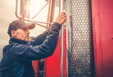 A man getting in his red truck after a commercial truck washing machine washed his truck before starting work.