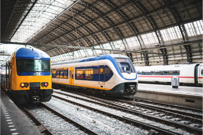 Two trains in a station observing the process of washing a train with automated washing system.